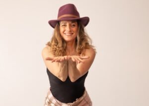 טאל בכובע בורדו, מושיטה כפות ידיים פתוחות בחיוך